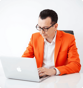 Мужчина в оранжевом пиджаке за ноутбуком