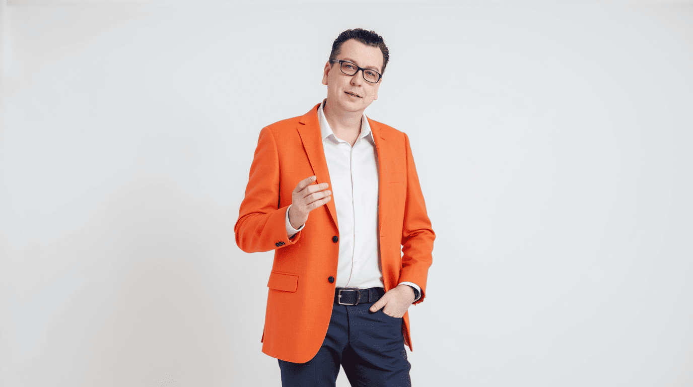 Мужчина в оранжевом пиджаке рассказывает о проработке этапов создания сайтов.